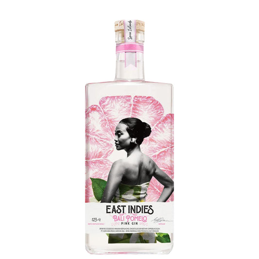 A bottle of East Indies Bali Romero Pink Gin on a solid white background. The clear glass bottle features a label with a large pink flower, a black-and-white portrait of a woman, and green leaves, topped with a gold seal.